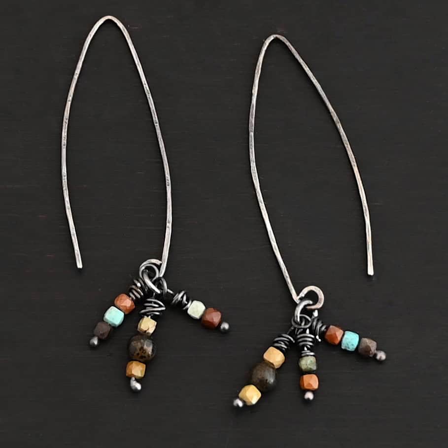"Imber" Earrings. Each earring is an upside down "U" Shape. Each earring has three small strands of silver hanging down from it, each with three beads on it. Each strand has silver wrapped around the top.