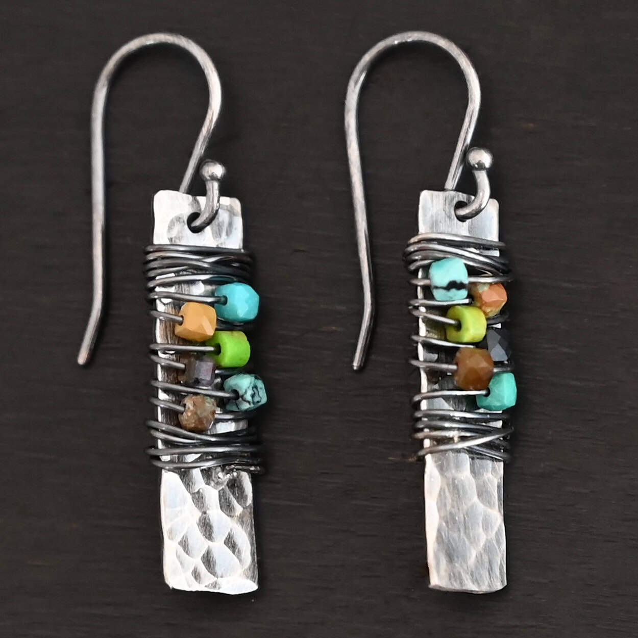 "Kea" Earrings. Each earring is a rectangular, vertical, hammered piece of silver. There is silver wire wrapped around the center of the earring, with five beads strung onto the wire.