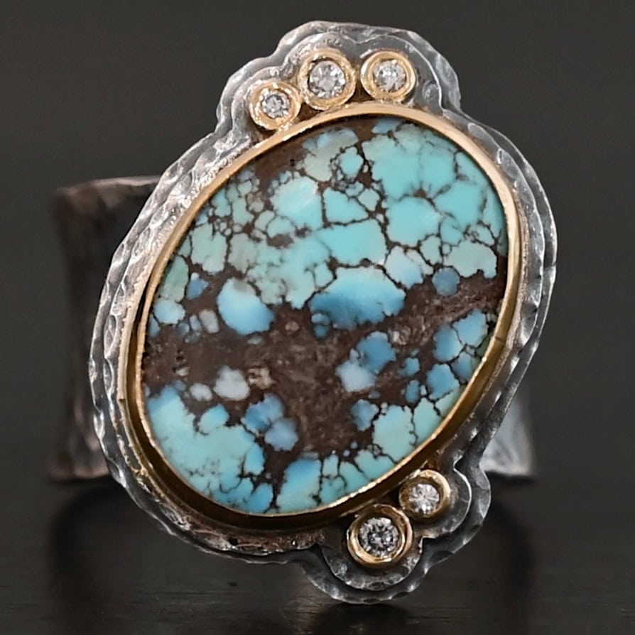 Sunshine and Blue Skies Ring "Sunshine & Blue Skies" Ring. There is a large oval shaped turquoise, set slightly askew, pointing towards the right. The turquoise is set in gold, as well as the diamonds. There are three small diamonds on the top and two on the bottom. Both follow the curve of the oval. There are two layers of sterling silver around the stone, and both are hammered. Ring band is thick silver and hammered.