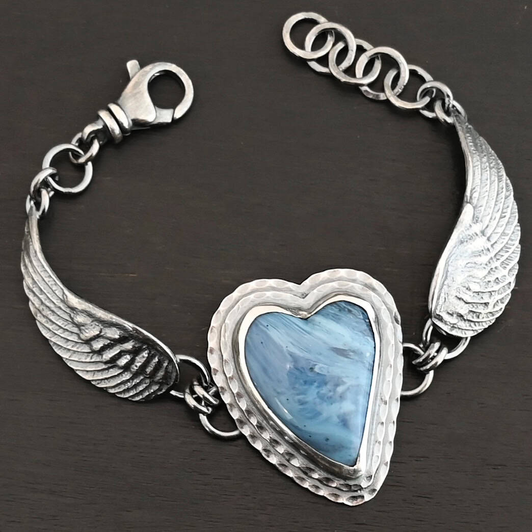 Waves Of Love Bracelet "Waves Of Love" Bracelet. The bracelet is a Leland Blue heart with medium sized angel wings on each side. The angel wings curve lightly so they can fit around the wrist. There is two layers of hammered sterling silver around the heart. Bracelet has a silver lobster claw clasp.