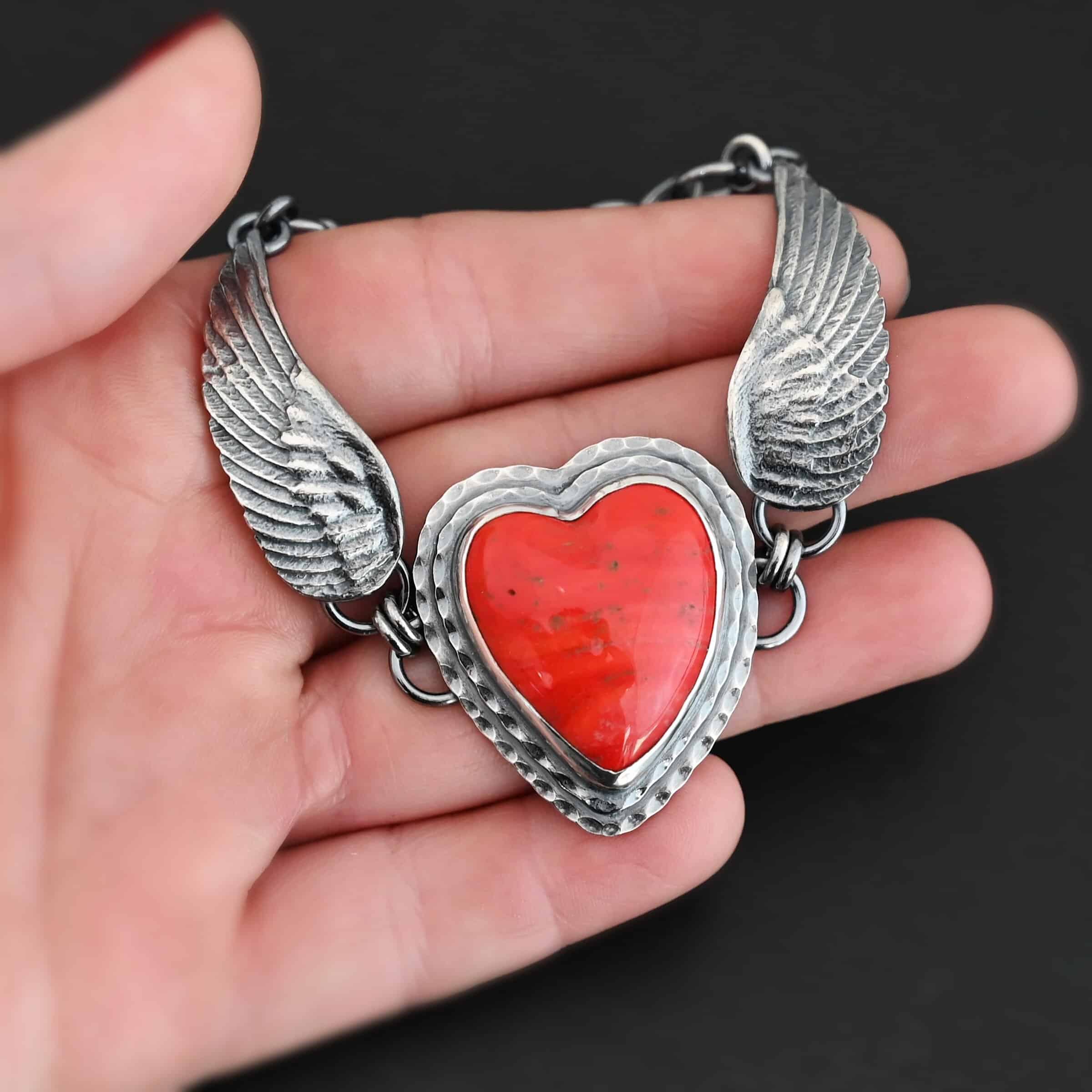 Heart On Fire Bracelet "Heart On Fire" Bracelet. The bracelet is a rosarita heart with medium sized angel wings on each side. The angel wings curve lightly so they can fit around the wrist. There is two layers of hammered sterling silver around the heart. Bracelet has a silver lobster claw clasp. Bracelet is shown up close in the fingertips of a hand.