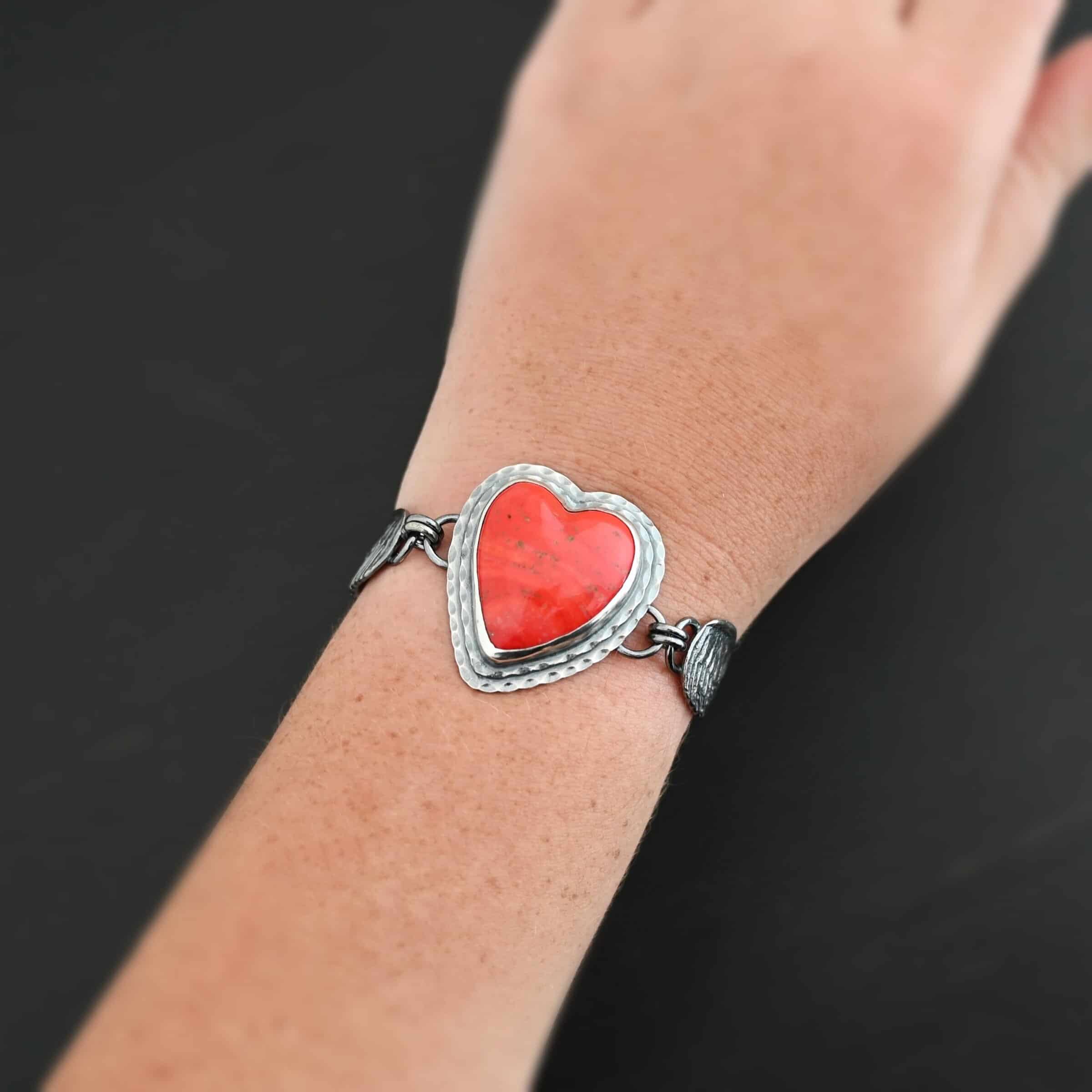 Heart On Fire Bracelet "Heart On Fire" Bracelet. The bracelet is a rosarita heart with medium sized angel wings on each side. The angel wings curve lightly so they can fit around the wrist. There is two layers of hammered sterling silver around the heart. Bracelet has a silver lobster claw clasp. Bracelet is shown up close by a model.