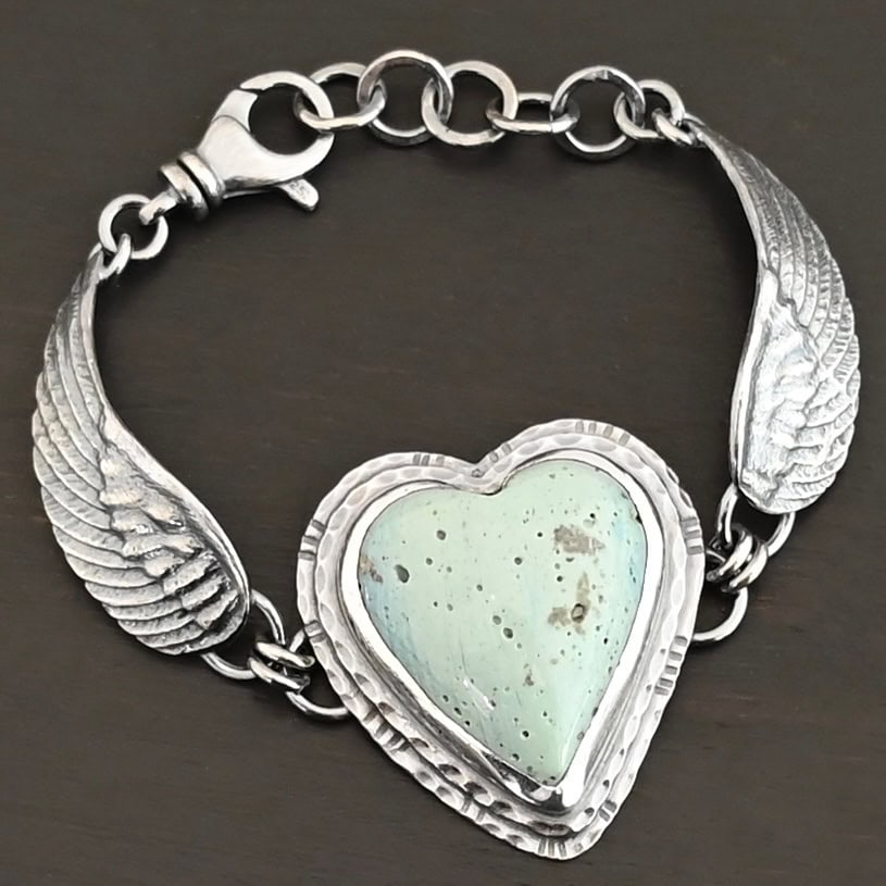 Vanessa Bracelet "Vanessa" Bracelet. The bracelet is a Leland Blue heart with medium sized angel wings on each side. The angel wings curve lightly so they can fit around the wrist. There is two layers of hammered sterling silver around the heart. Bracelet has a silver lobster claw clasp.