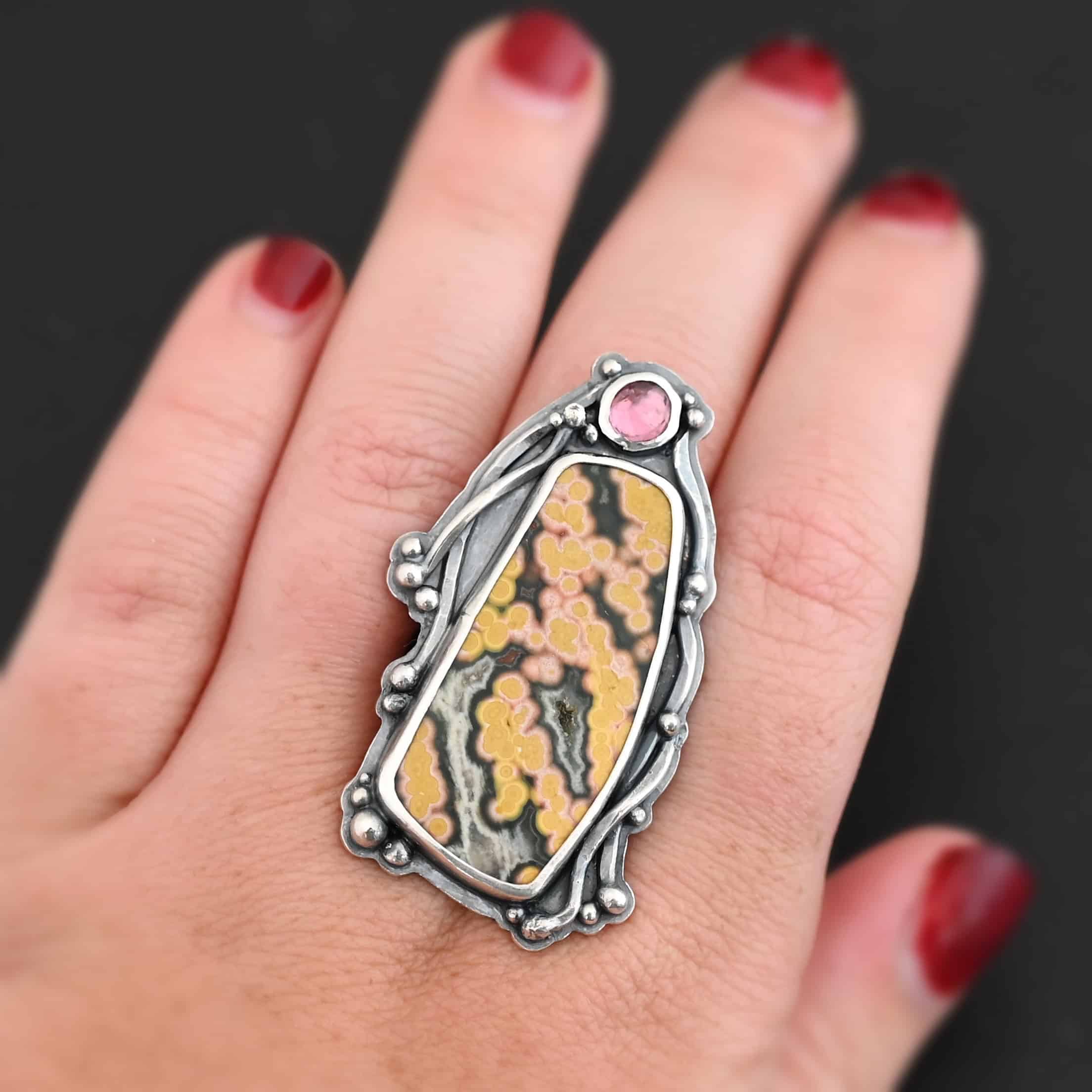Yellow Rose Of Texas Ring "Yellow Rose Of Texas" Ring. There is a rectangular ocean jasper, set vertically. There is a smaller circular pink tourmaline above it. There are lots of wavy, hammered lines of silver around the stones. Ring is double banded so it can be adjusted. Ring is shown up close by a model.