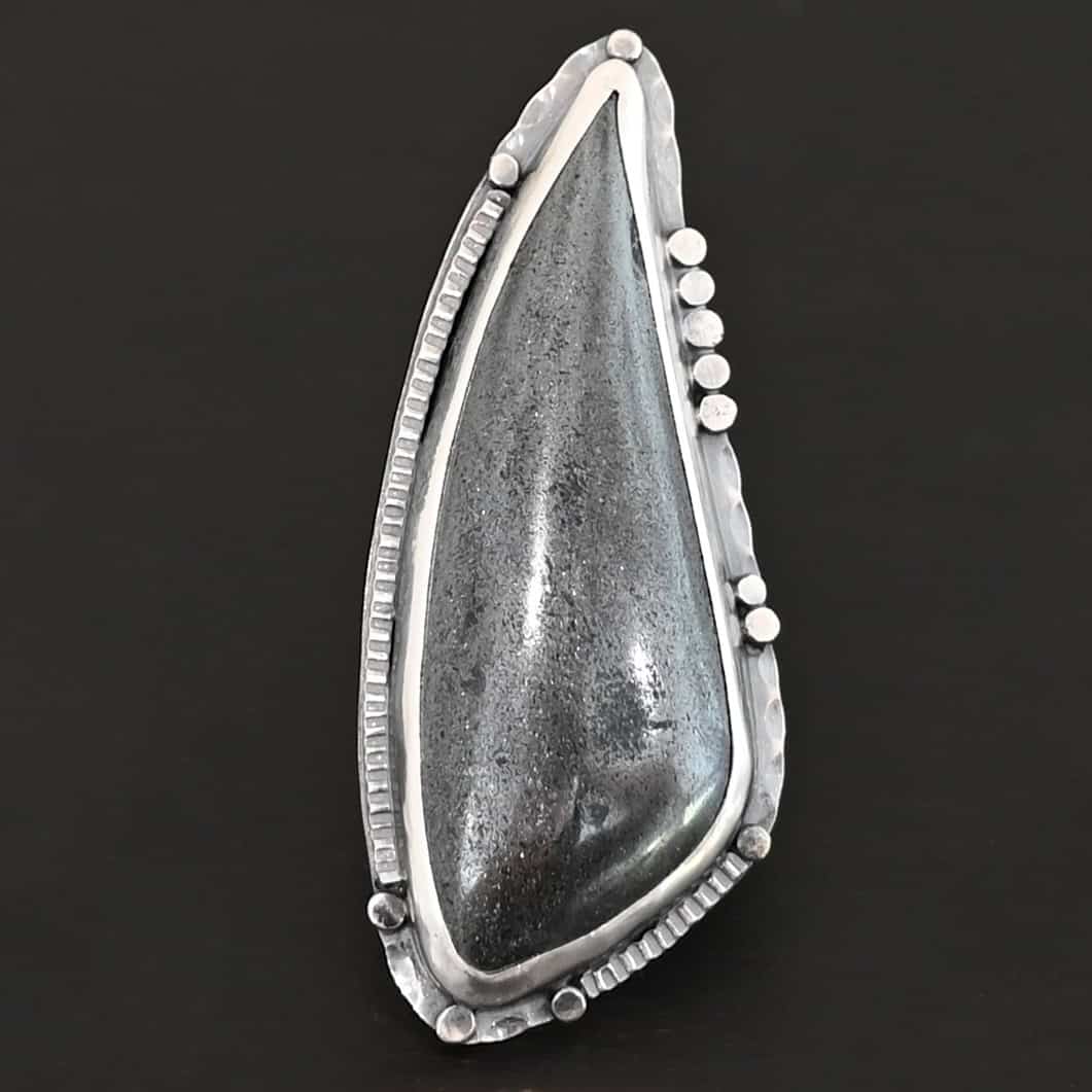 Wandering Star Ring "Wandering Star" Ring. The stone is large, and primarily marquise shaped with a sparkly gray color. The silver around it has hammered lines and flat dots of silver scattered around it.