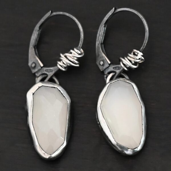 "Gracie" Earrings. The earrings are oval rose cut moonstones hanging vertically. There are silver leverback ear wires with silver wire wrapped around part of them.
