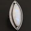 "Artemis Ring" The ring is large, marquise, vertical moonstone. There is a ball of silver on the top and bottom of it. There is textured silver around it, and a thin layer around that which is hammered.