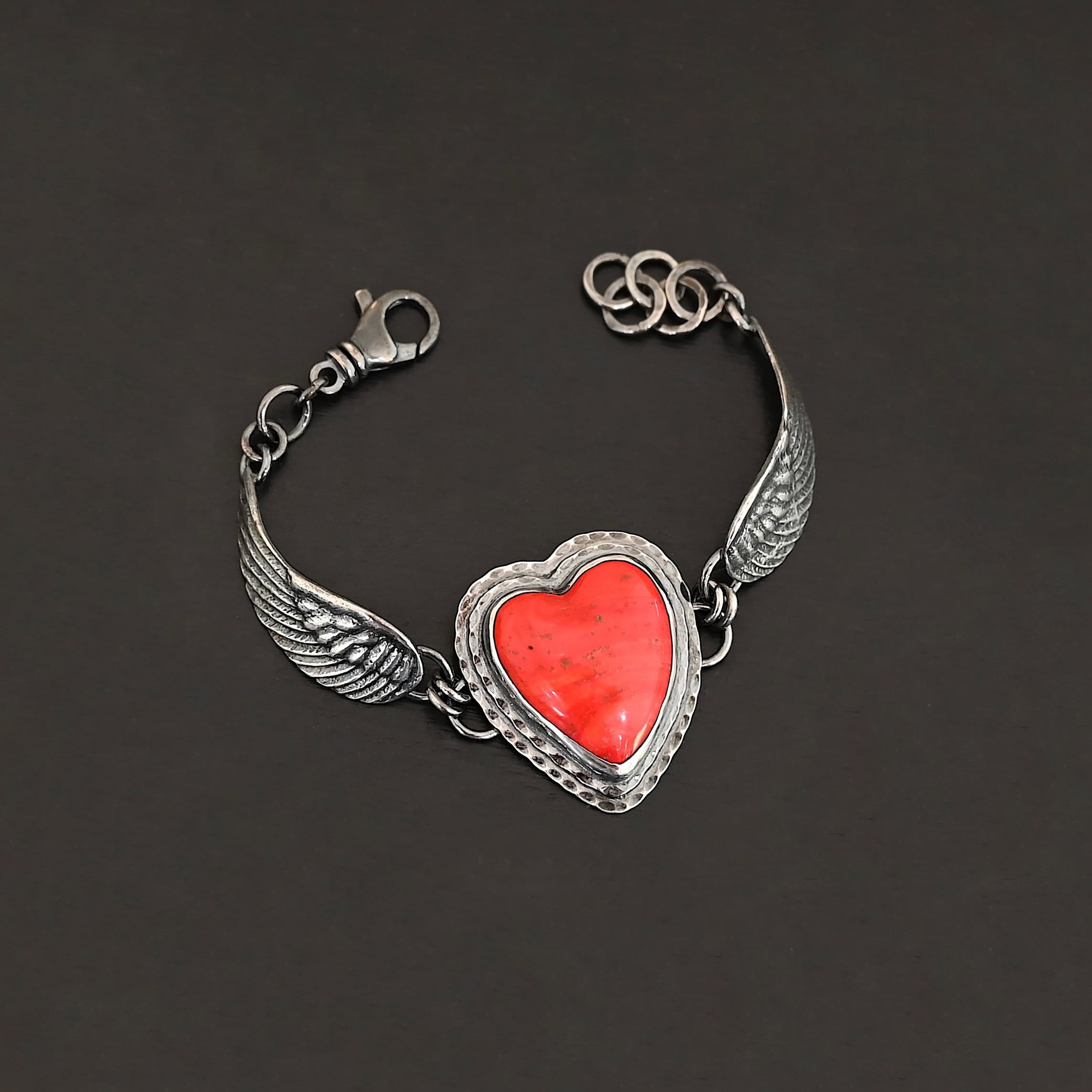 Heart On Fire Bracelet new "Heart On Fire" Bracelet. The bracelet is a rosarita heart with medium sized angel wings on each side. The angel wings curve lightly so they can fit around the wrist. There is two layers of hammered sterling silver around the heart. Bracelet has a silver lobster claw clasp.