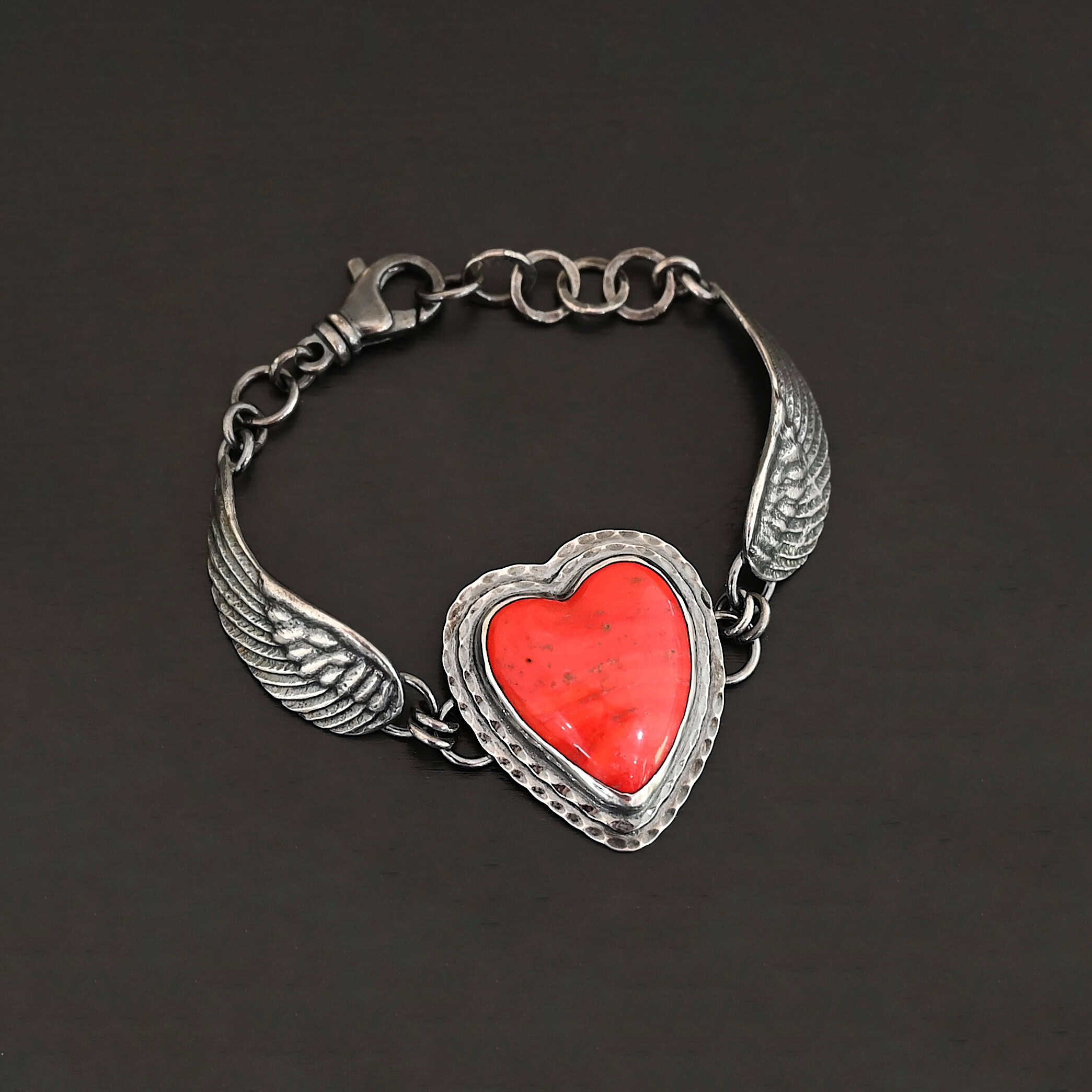 Heart On Fire Bracelet new "Heart On Fire" Bracelet. The bracelet is a rosarita heart with medium sized angel wings on each side. The angel wings curve lightly so they can fit around the wrist. There is two layers of hammered sterling silver around the heart. Bracelet has a silver lobster claw clasp.