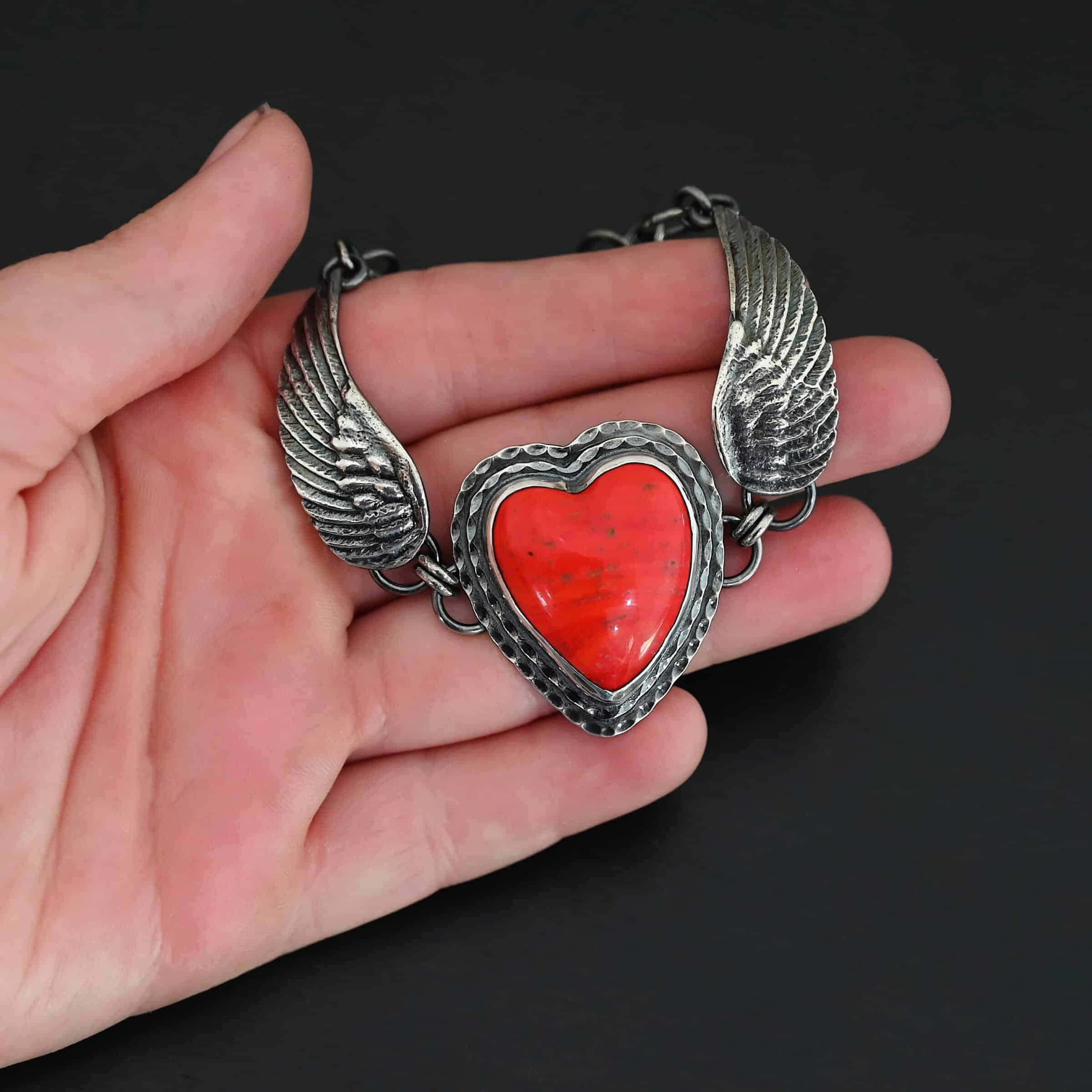 Heart On Fire Bracelet new "Heart On Fire" Bracelet. The bracelet is a rosarita heart with medium sized angel wings on each side. The angel wings curve lightly so they can fit around the wrist. There is two layers of hammered sterling silver around the heart. Bracelet has a silver lobster claw clasp. Bracelet is shown up close in the fingertips of a hand.
