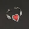 "Cerise" Bracelet. The bracelet is a rosarita heart with medium sized angel wings on each side. The angel wings curve lightly so they can fit around the wrist. There is two layers of hammered sterling silver around the heart. Bracelet has a silver lobster claw clasp.