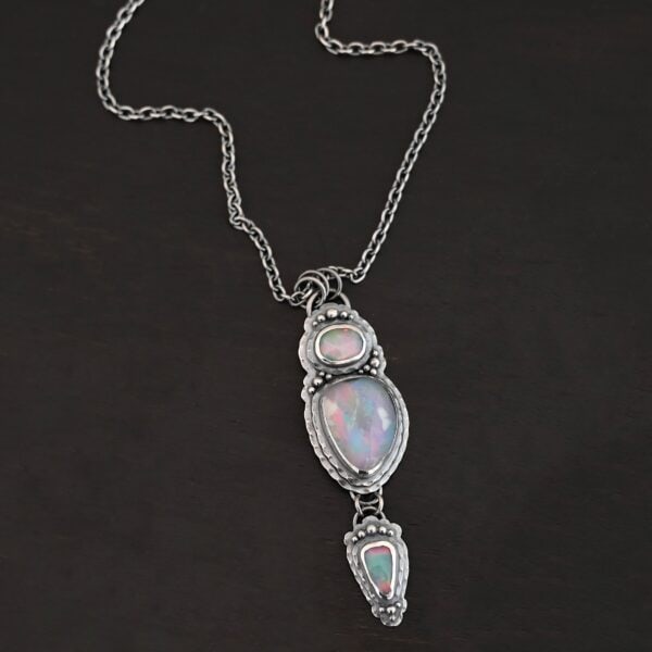 "Blue Moon Magic" Necklace. There are three opals in a line down. The top one is a small horizontal oval. The next one is a larger, vertical opal. The bottom one is a small triangle. Each one has silver ball detail surrounding it, as well as hammered silver.