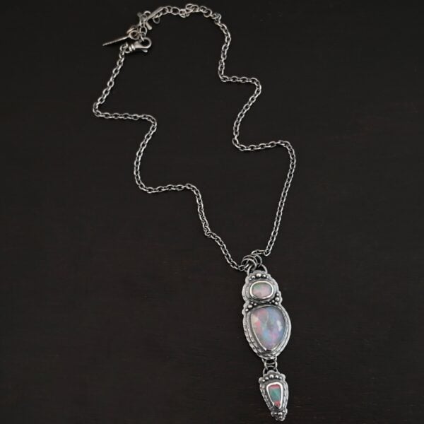 "Blue Moon Magic" Necklace. There are three opals in a line down. The top one is a small horizontal oval. The next one is a larger, vertical opal. The bottom one is a small triangle. Each one has silver ball detail surrounding it, as well as hammered silver.