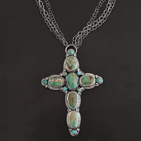 "Firm In Faith" Necklace. Necklace is a large cross shape with six oval turquoise creating the cross shaped eight small circular turquoise around the rest of the pendant. Chain is multiple strands that meet at the back.