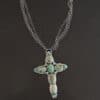 "Firm In Faith" Necklace. Necklace is a large cross shape with six oval turquoise creating the cross shape and eight small circular turquoise around the rest of the pendant. Chain is multiple strands that meet at the back.