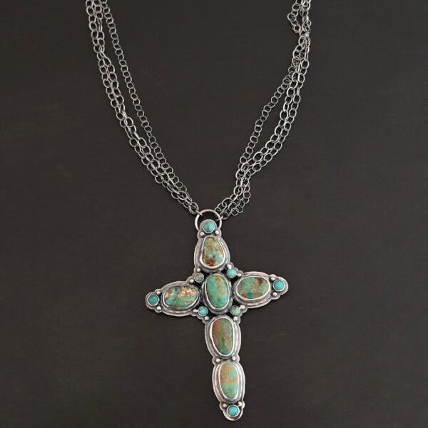 "Firm In Faith" Necklace. Necklace is a large cross shape with six oval turquoise creating the cross shape and eight small circular turquoise around the rest of the pendant. Chain is multiple strands that meet at the back.