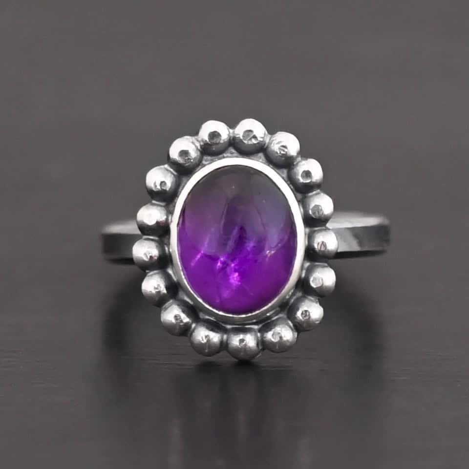 Viola Ring "Viola" Ring. Sterling Silver & Amethyst. There is an oval, vertical amethyst in the center with balls of silver circling all the way around it. Ring band is smooth & lightly oxidized.