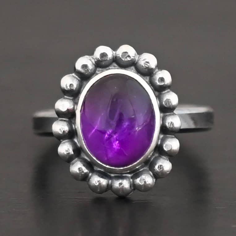 Viola Ring "Viola" Ring. Sterling Silver & Amethyst. There is an oval, vertical amethyst in the center with balls of silver circling all the way around it. Ring band is smooth & lightly oxidized.
