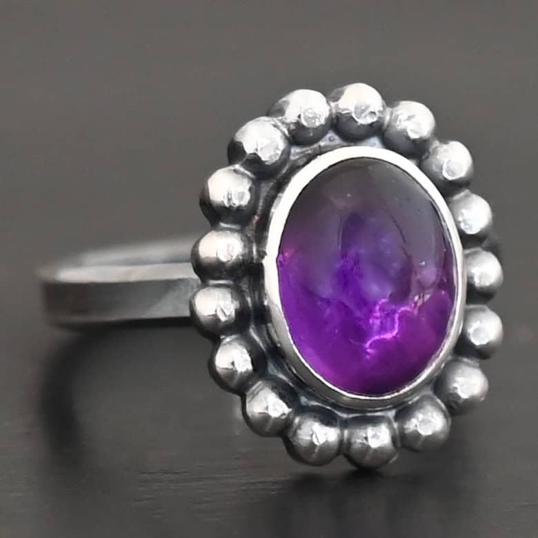 Viola Ring "Viola" Ring. Sterling Silver & Amethyst. There is an oval, vertical amethyst in the center with balls of silver circling all the way around it. Ring band is smooth & lightly oxidized.
