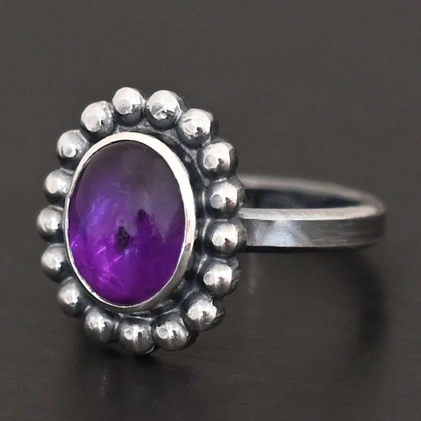 Viola Ring "Viola" Ring. Sterling Silver & Amethyst. There is an oval, vertical amethyst in the center with balls of silver circling all the way around it. Ring band is smooth & lightly oxidized.
