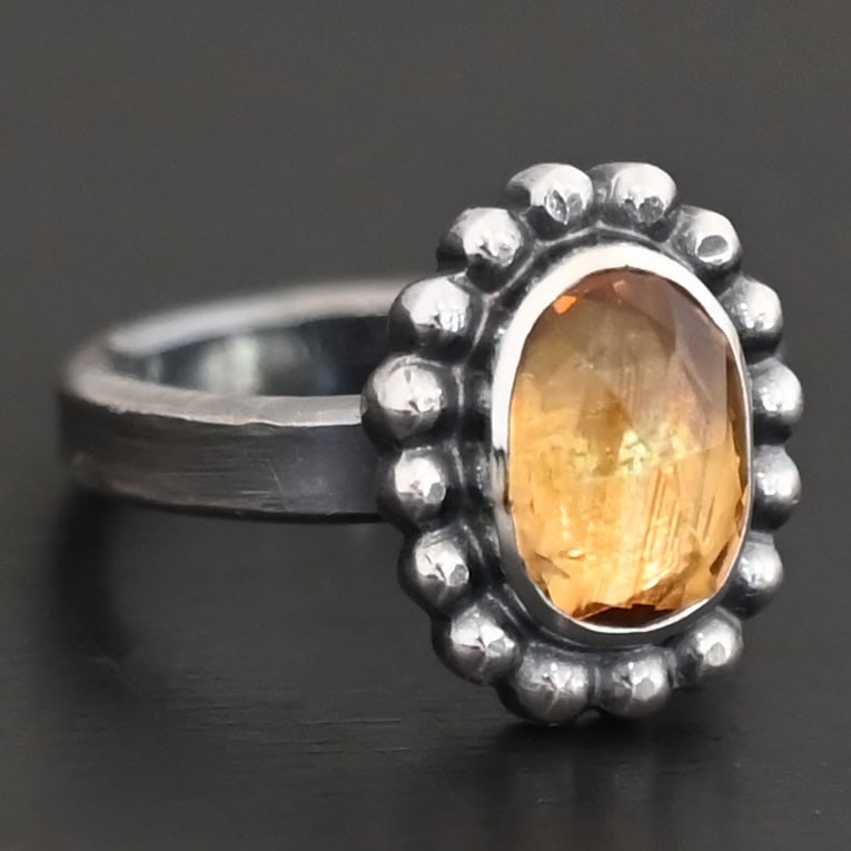 "Giallo" Ring. Sterling Silver & Citrine. There is an oval, vertical citrine in the center with balls of silver circling all the way around it. Ring band is smooth & lightly oxidized.