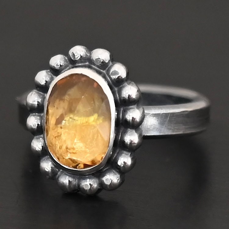 "Giallo" Ring. Sterling Silver & Citrine. There is an oval, vertical citrine in the center with balls of silver circling all the way around it. Ring band is smooth & lightly oxidized.