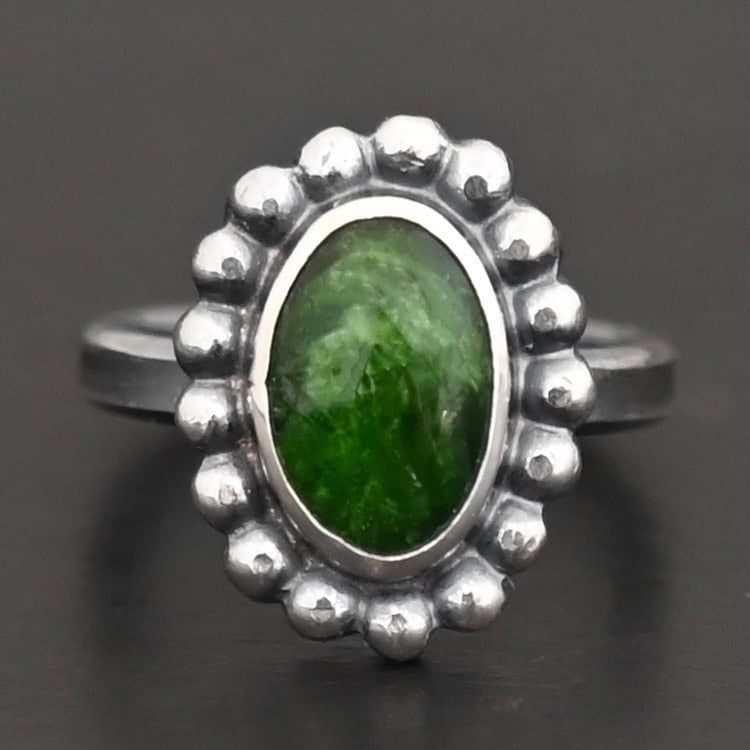 "New Leaf" Ring. Sterling Silver & Chrome Diopside. There is an oval, vertical chrome diopside in the center with balls of silver circling all the way around it. Ring band is smooth & lightly oxidized.