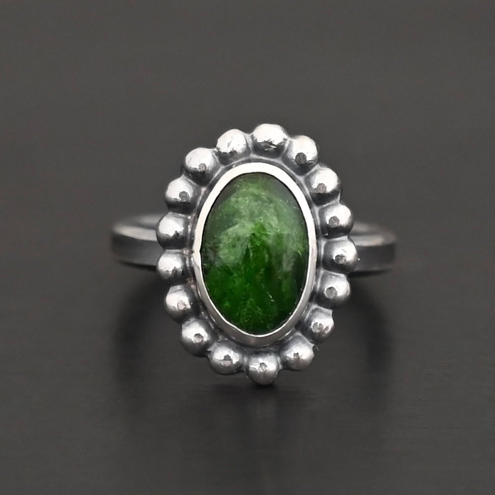 "New Leaf" Ring. Sterling Silver & Chrome Diopside. There is an oval, vertical chrome diopside in the center with balls of silver circling all the way around it. Ring band is smooth & lightly oxidized.