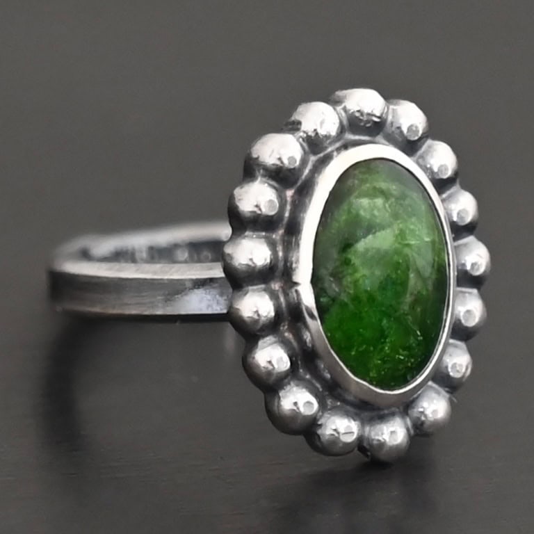 "New Leaf" Ring. Sterling Silver & Chrome Diopside. There is an oval, vertical chrome diopside in the center with balls of silver circling all the way around it. Ring band is smooth & lightly oxidized.