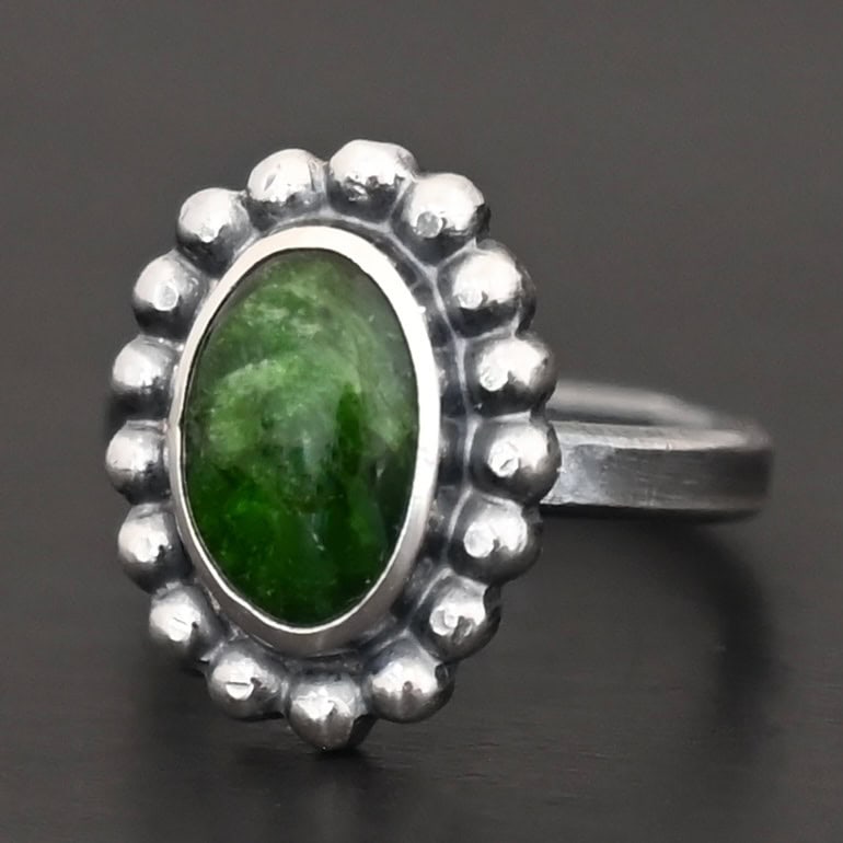 "New Leaf" Ring. Sterling Silver & Chrome Diopside. There is an oval, vertical chrome diopside in the center with balls of silver circling all the way around it. Ring band is smooth & lightly oxidized.
