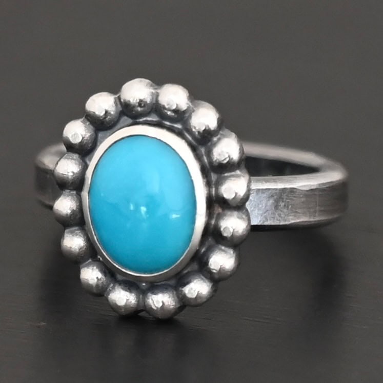 "Sky & Spirit" Ring. Sterling Silver & Turquoise. There is an oval, vertical turquoise in the center with balls of silver circling all the way around it. Ring band is smooth & lightly oxidized.