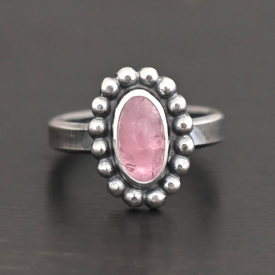 Rosalyn Ring "Rosalyn" Ring. Sterling Silver & Tourmaline. There is an oval, vertical tourmaline in the center with balls of silver circling all the way around it. Ring band is smooth & lightly oxidized.