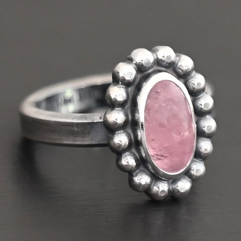 Rosalyn Ring "Rosalyn" Ring. Sterling Silver & Tourmaline. There is an oval, vertical tourmaline in the center with balls of silver circling all the way around it. Ring band is smooth & lightly oxidized.