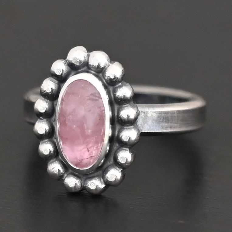 Rosalyn Ring "Rosalyn" Ring. Sterling Silver & Tourmaline. There is an oval, vertical tourmaline in the center with balls of silver circling all the way around it. Ring band is smooth & lightly oxidized.