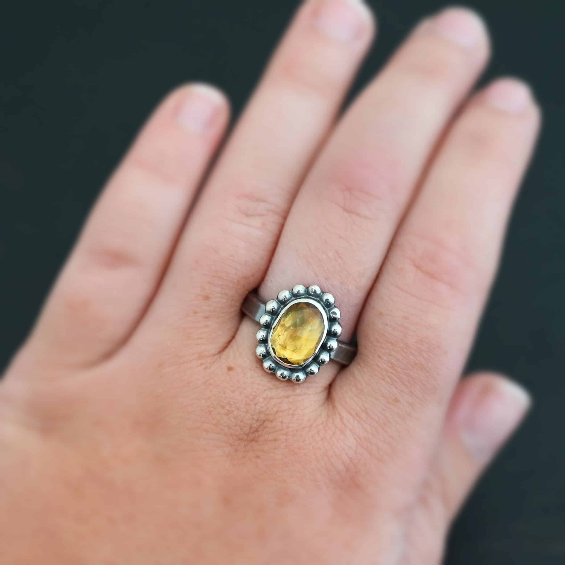 "Giallo" Ring. Sterling Silver & Citrine. There is an oval, vertical citrine in the center with balls of silver circling all the way around it. Ring band is smooth & lightly oxidized.