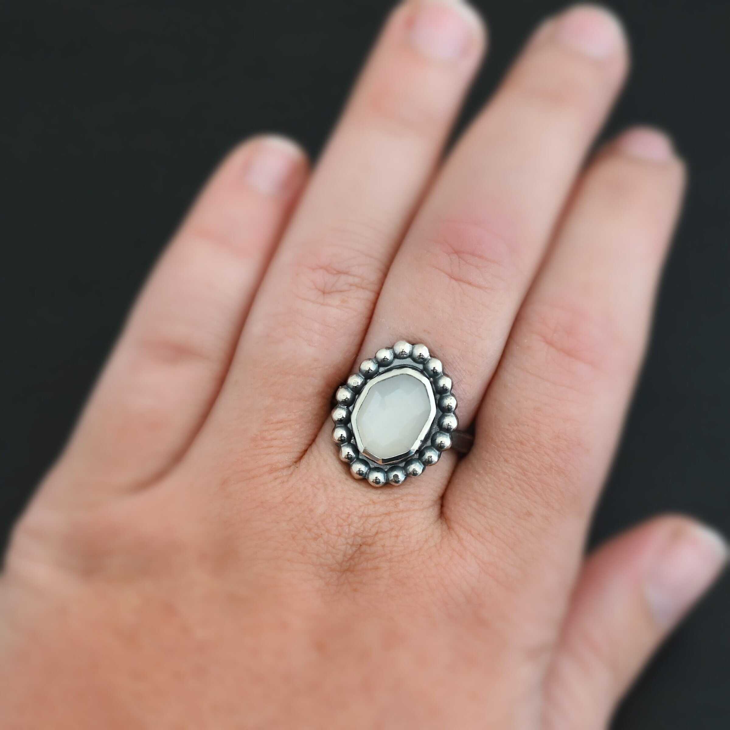 "Adelina" Ring. Sterling Silver & Moonstone. There is an oval, vertical moonstone in the center with balls of silver circling all the way around it. Ring band is smooth & lightly oxidized.