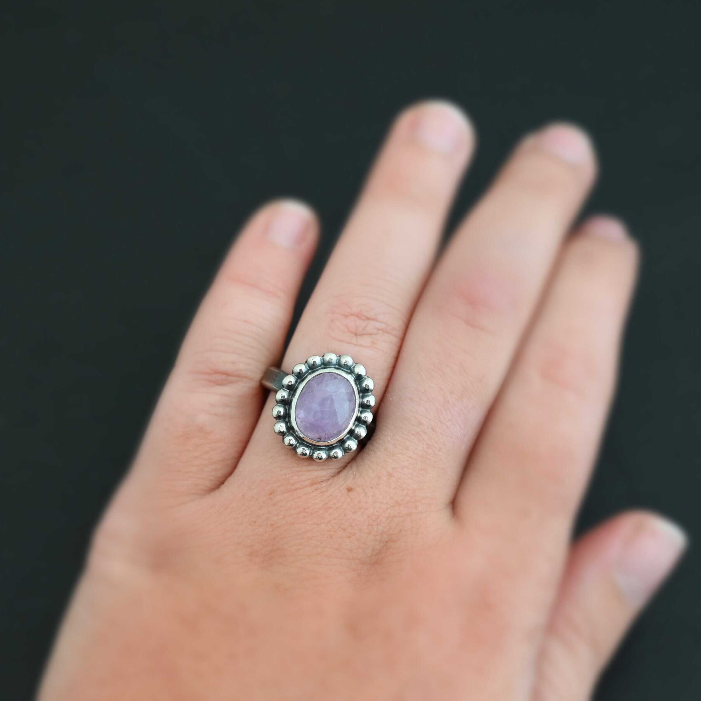 "Pink Glow" Ring. Sterling Silver & Kunzite. There is an oval, vertical kunzite in the center with balls of silver circling all the way around it. Ring band is smooth & lightly oxidized.