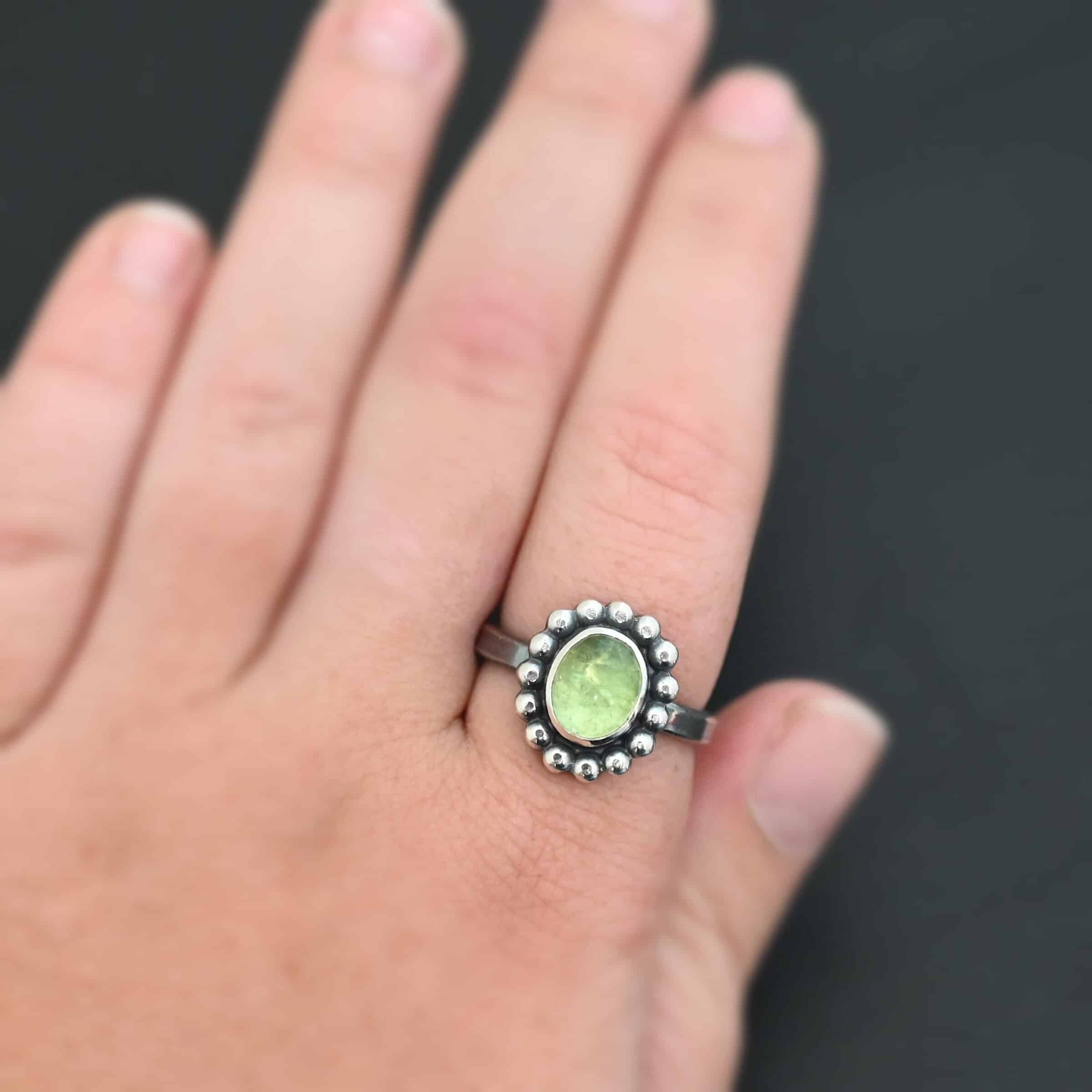 Maven Ring "Maven" Ring. Sterling Silver & Tourmaline. There is an oval, vertical tourmaline in the center with balls of silver circling all the way around it. Ring band is smooth & lightly oxidized.