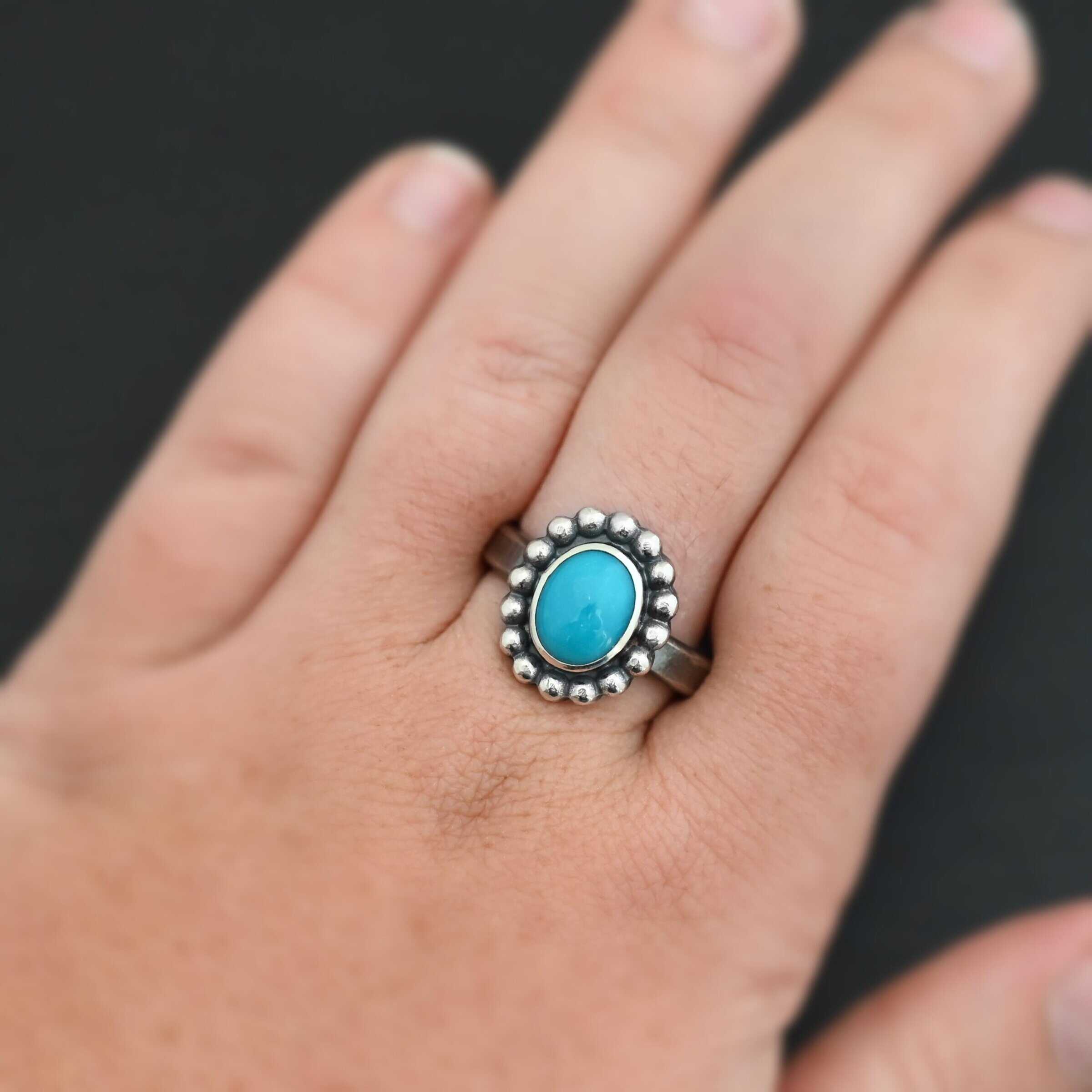 "Sky & Spirit" Ring. Sterling Silver & Turquoise. There is an oval, vertical turquoise in the center with balls of silver circling all the way around it. Ring band is smooth & lightly oxidized.