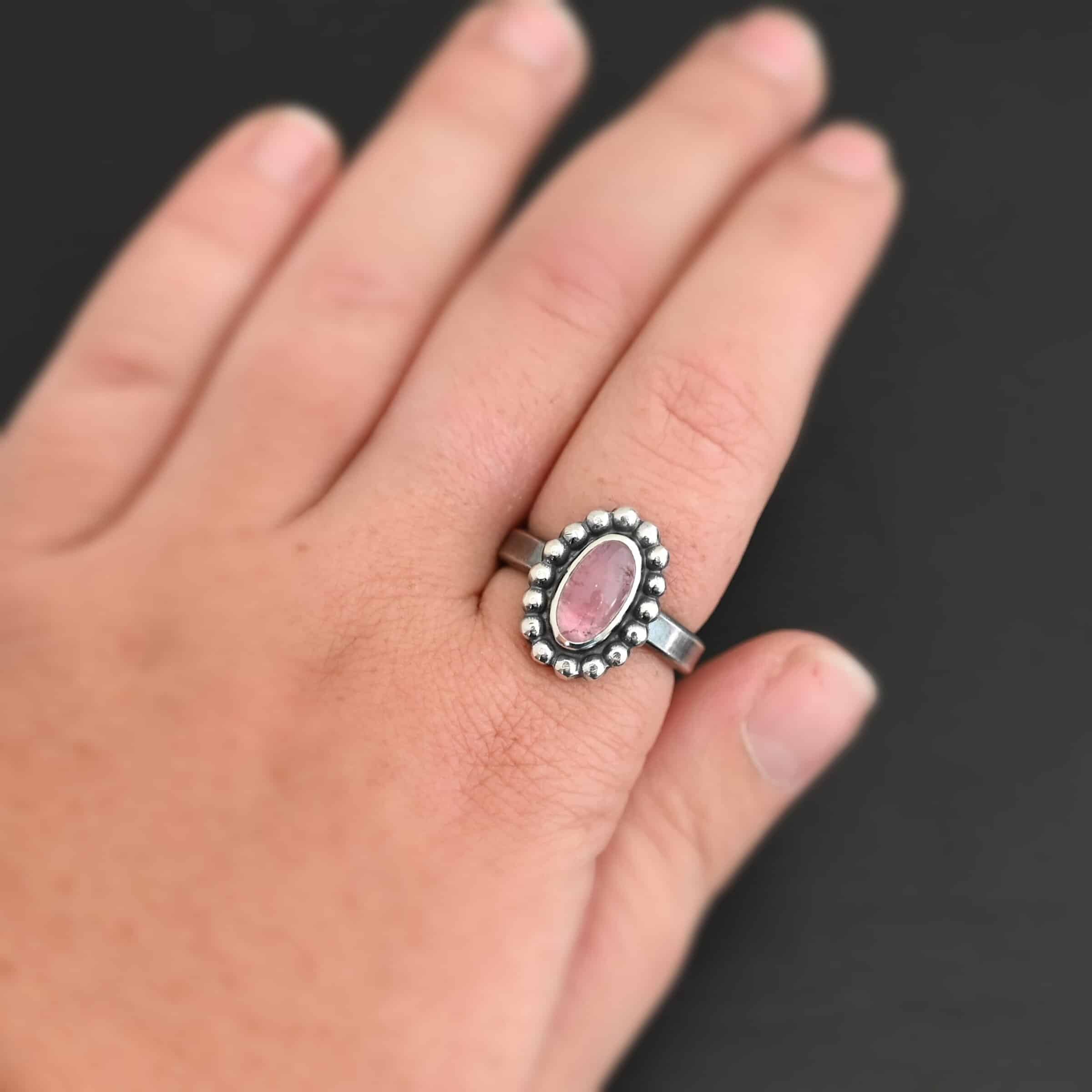 Rosalyn Ring "Rosalyn" Ring. Sterling Silver & Tourmaline. There is an oval, vertical tourmaline in the center with balls of silver circling all the way around it. Ring band is smooth & lightly oxidized.