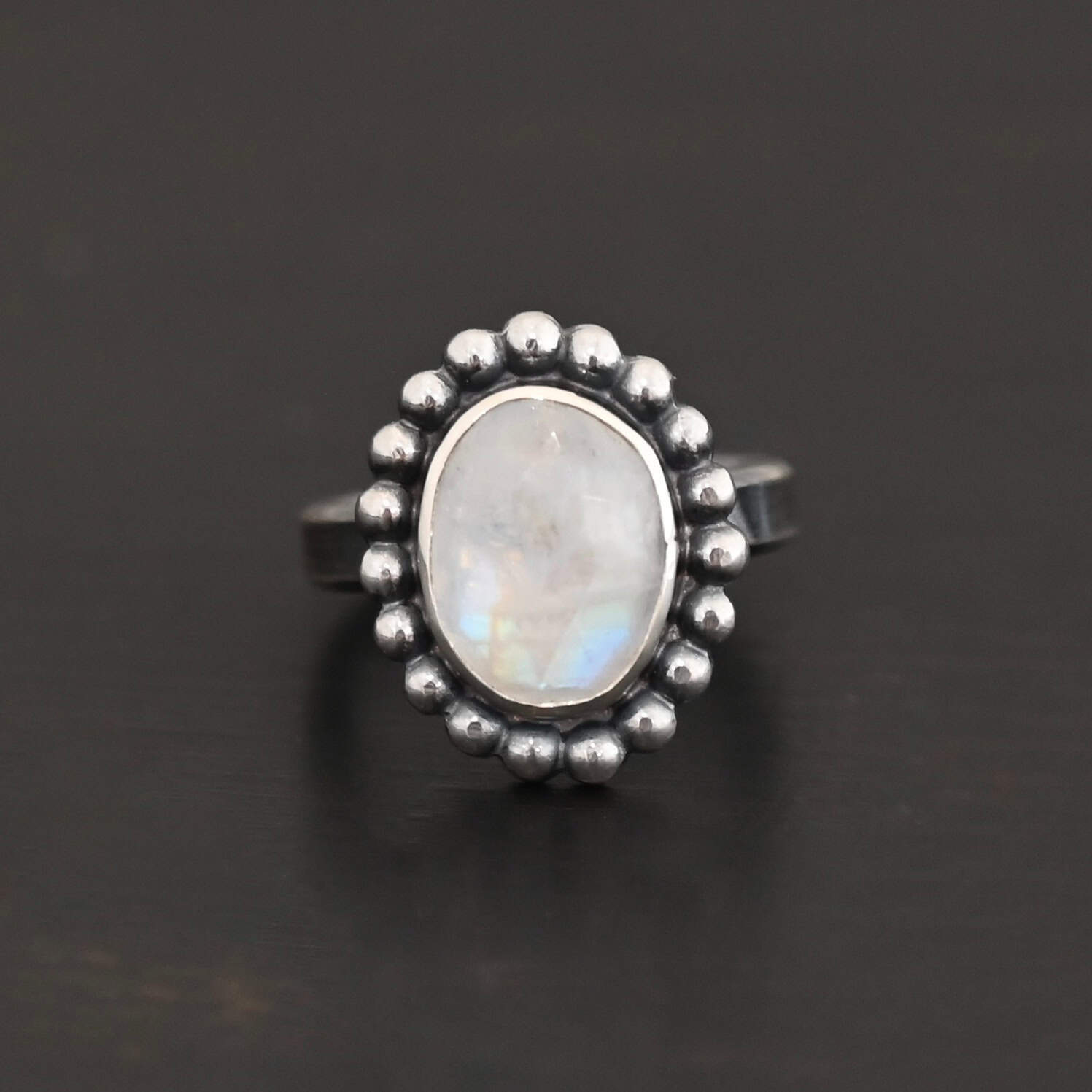Shining Dreams Ring "Shining Dreams" Ring. Sterling Silver & Moonstone. There is an oval, vertical moonstone in the center with balls of silver circling all the way around it. Ring band is smooth & lightly oxidized.