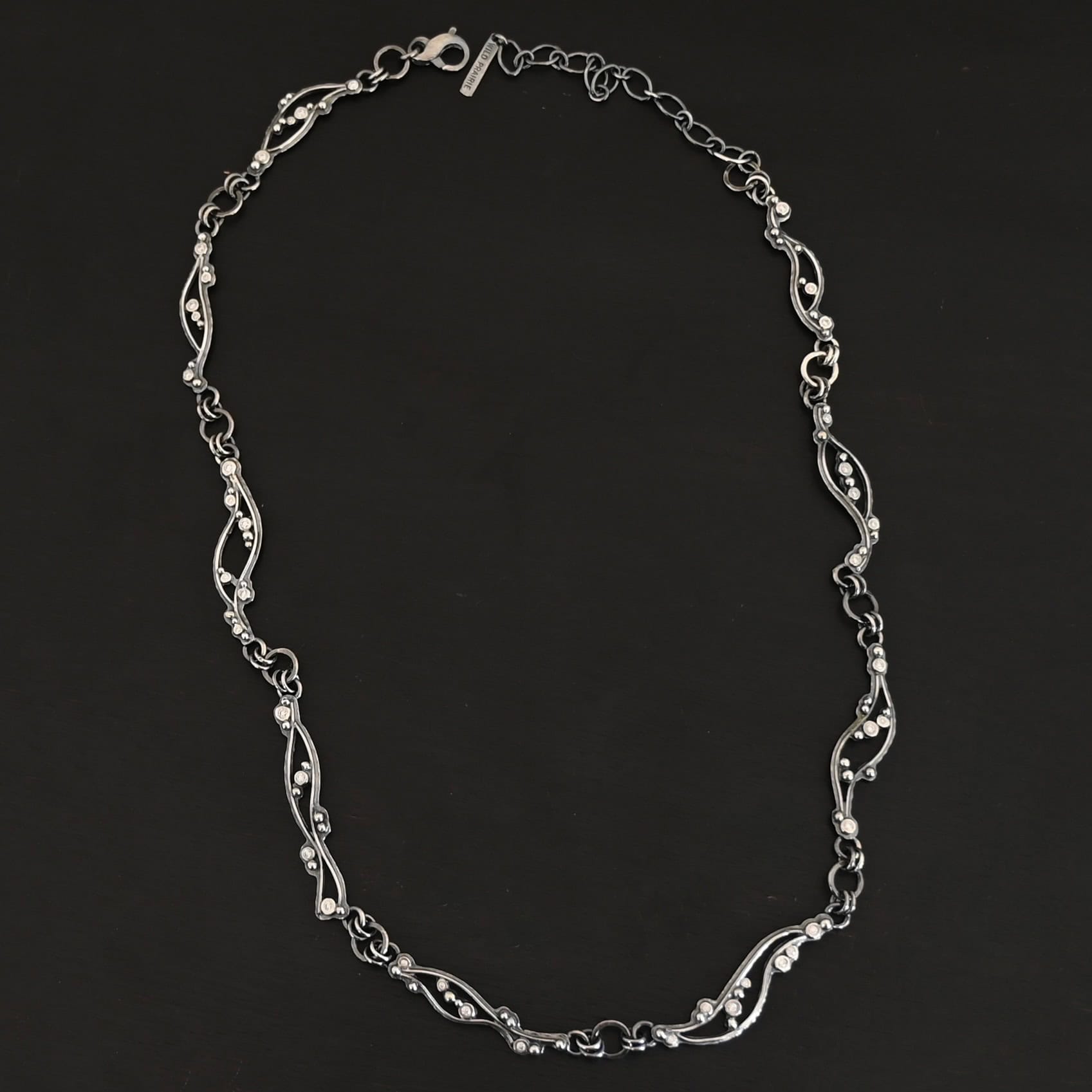 Dorthea Necklace "Dorthea" Necklace. There are nine wavy pieces of silver connected together in a collar necklace. Each piece has silver ball detail and multiple moissanites surrounding them. The lines on the waves are hammered lightly.