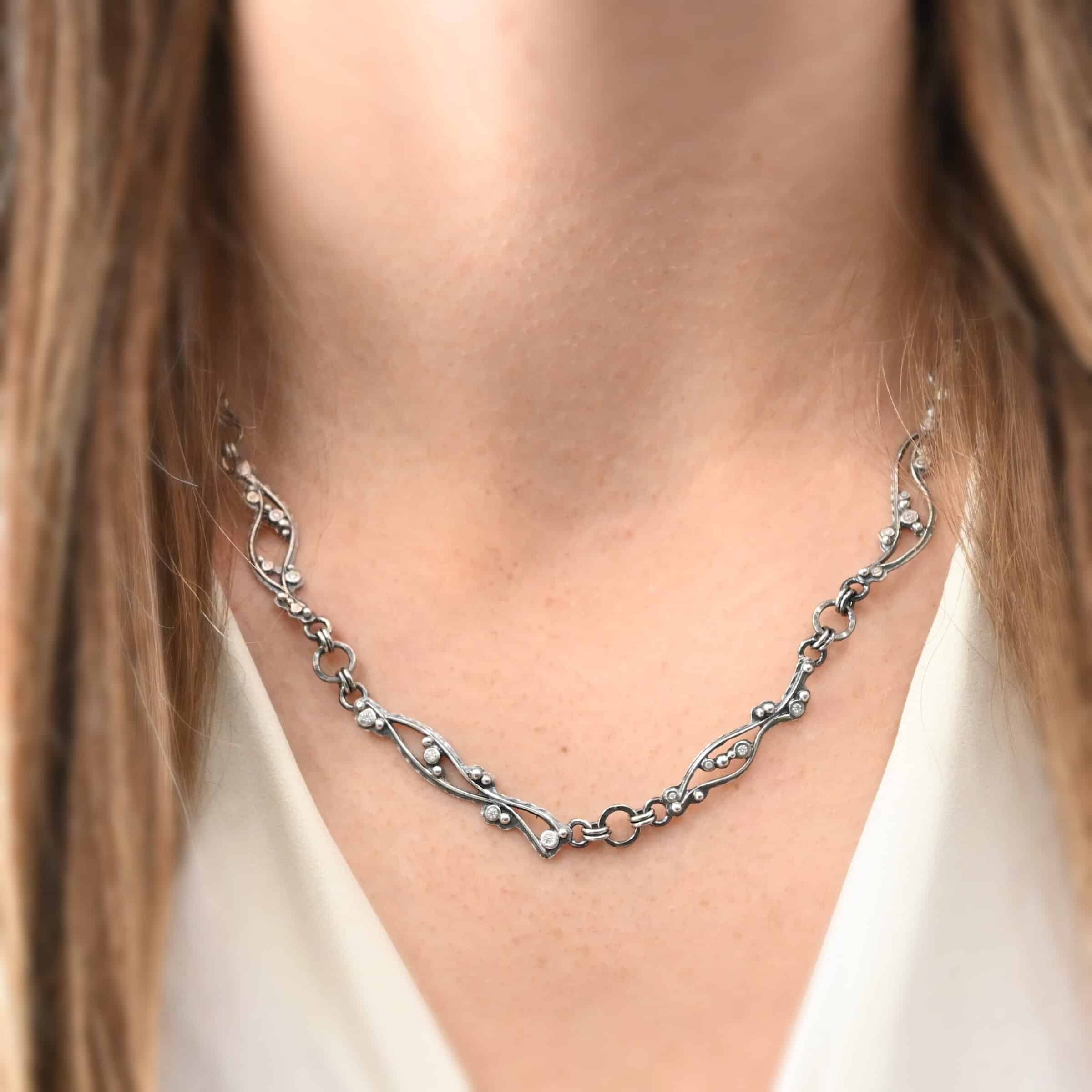 Dorthea Necklace "Dorthea" Necklace. There are nine wavy pieces of silver connected together in a collar necklace. Each piece has silver ball detail and multiple moissanites surrounding them. The lines on the waves are hammered lightly.