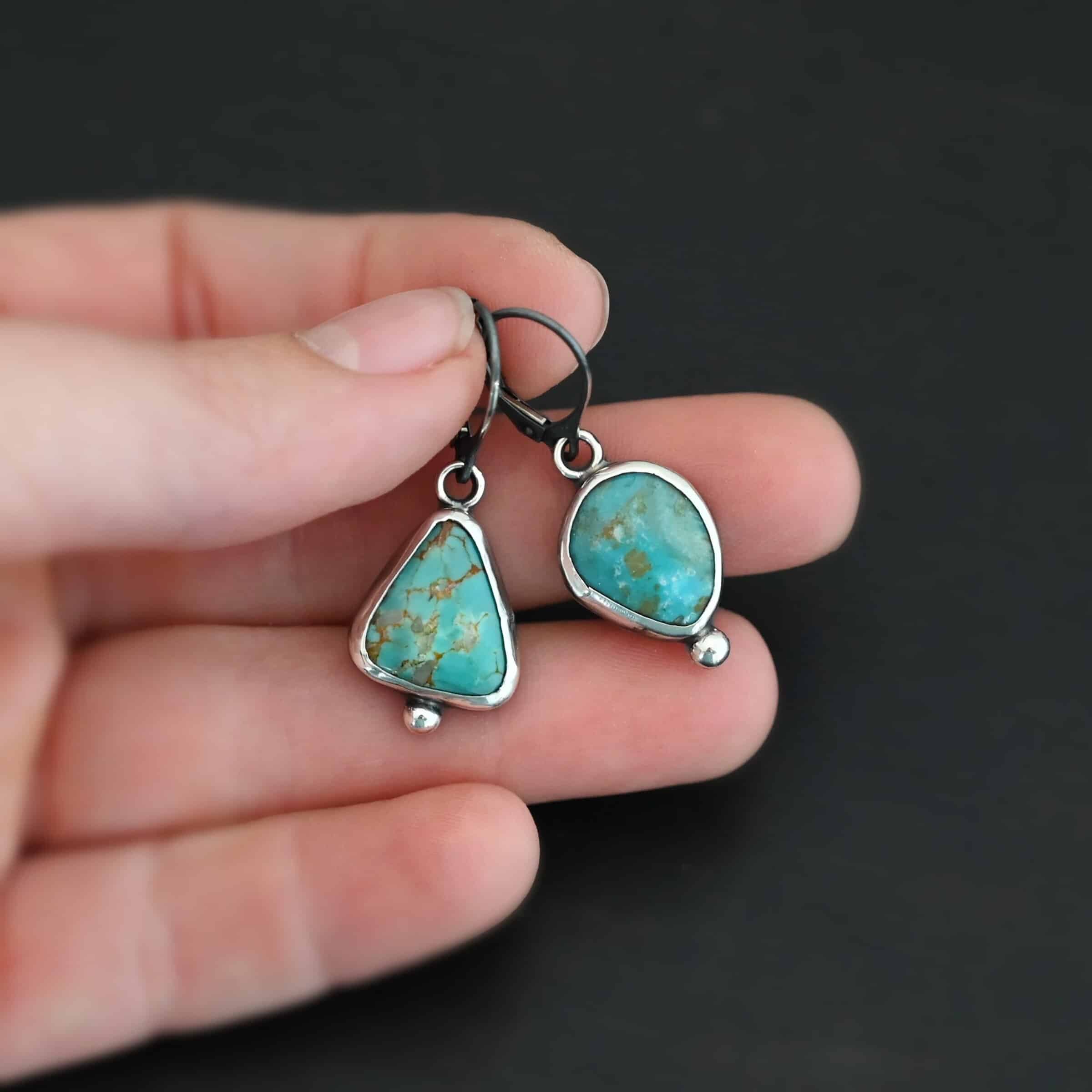 "Ida" Earrings. Sterling Silver & Turquoise. Left earring has a triangular turquoise and right earring has an oval turquoise. Each one has a ball of silver beneath it and silver ear wires.
