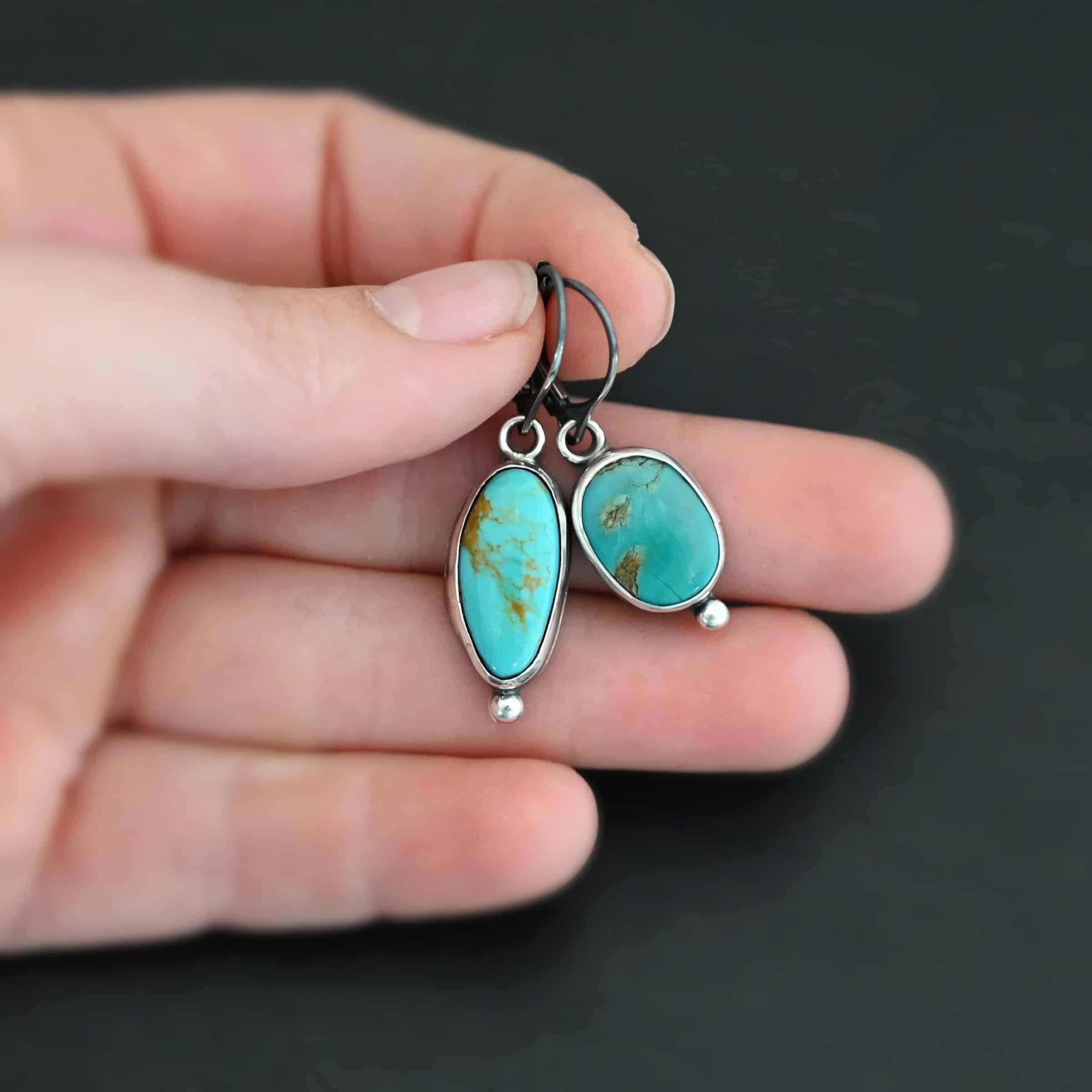 "Vivi" Earrings. Sterling Silver & Turquoise. Left earring has a circular turquoise and right earring is an oval. Each one has a ball of silver beneath it and silver ear wires.