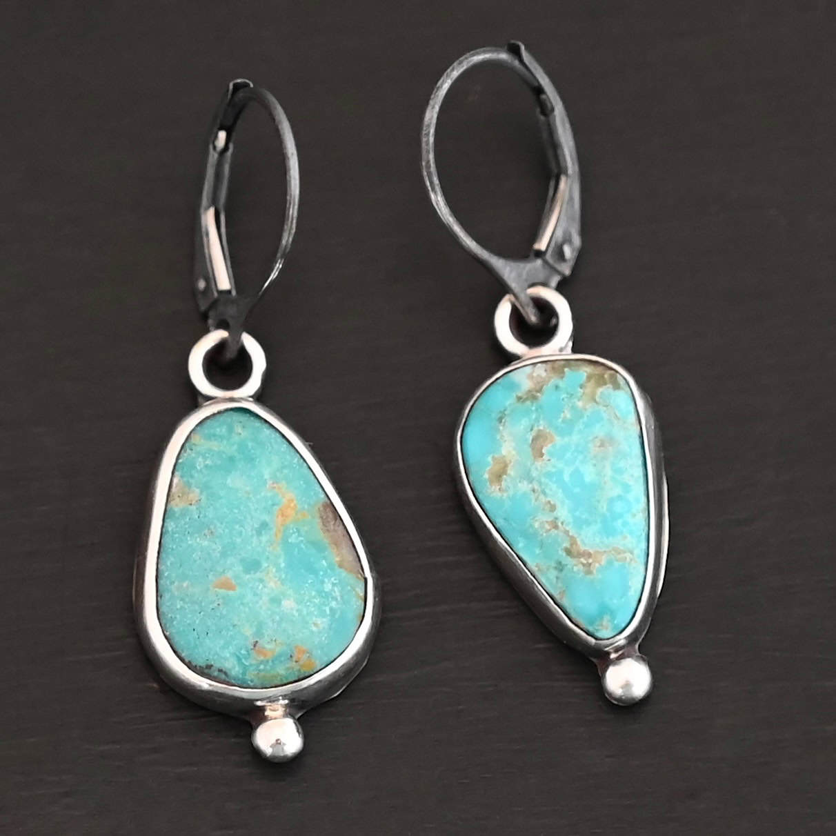 Lottie Earrings "Lottie" Earrings. Sterling Silver & Turquoise. Each earring has a primarily oval shaped stone. Each one has a ball of silver beneath it and silver ear wires.