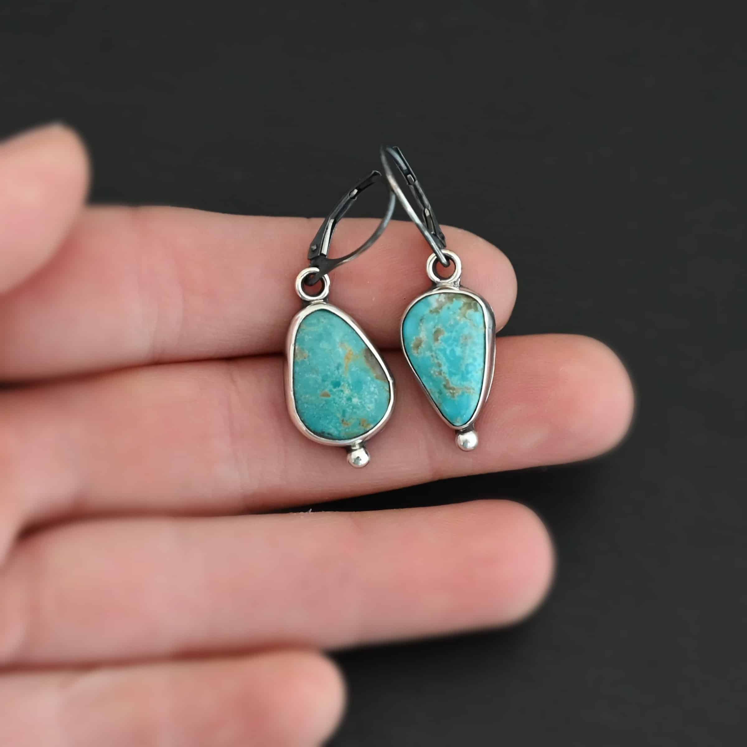 Lottie Earrings "Lottie" Earrings. Sterling Silver & Turquoise. Each earring has a primarily oval shaped stone. Each one has a ball of silver beneath it and silver ear wires.