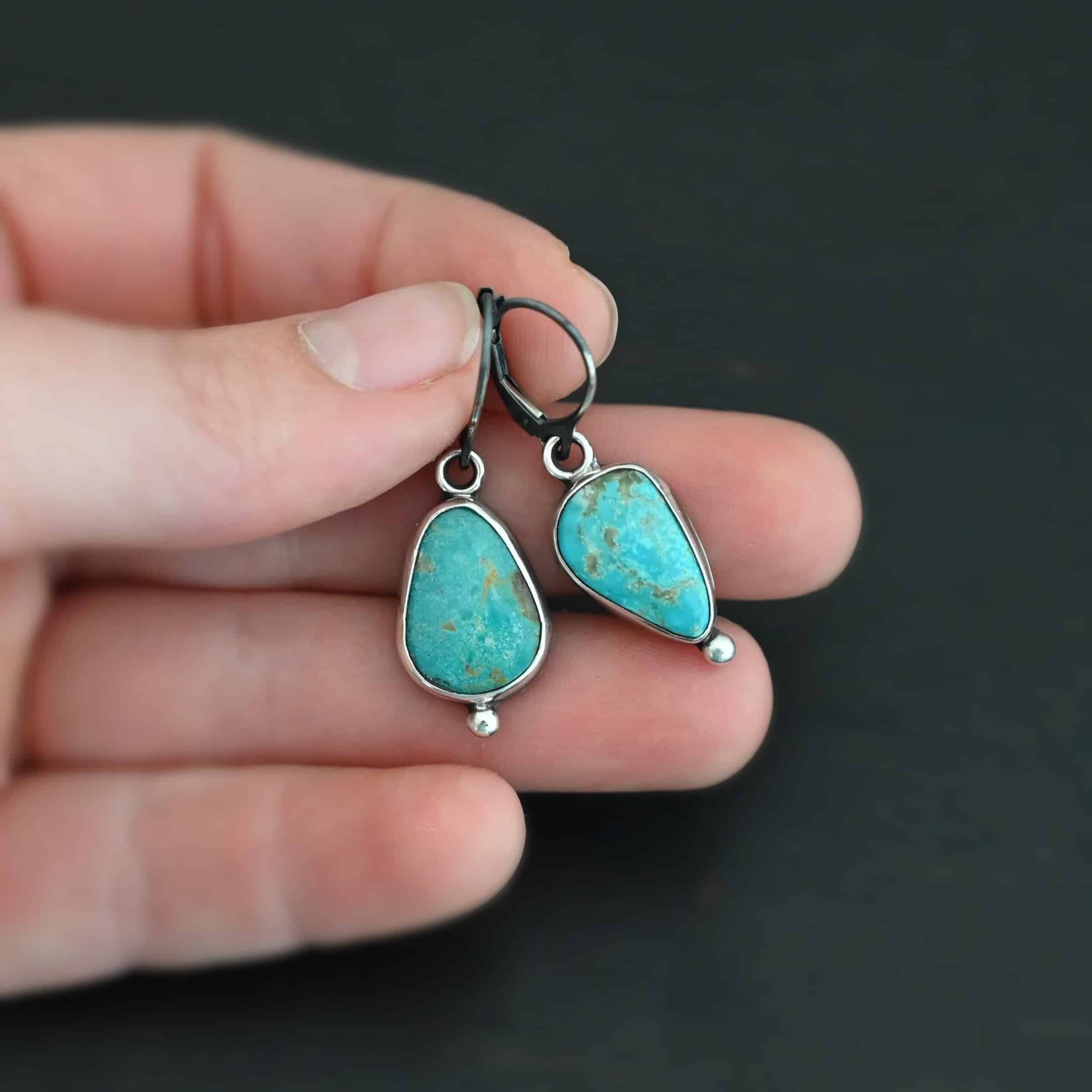 Lottie Earrings "Lottie" Earrings. Sterling Silver & Turquoise. Each earring has a primarily oval shaped stone. Each one has a ball of silver beneath it and silver ear wires.