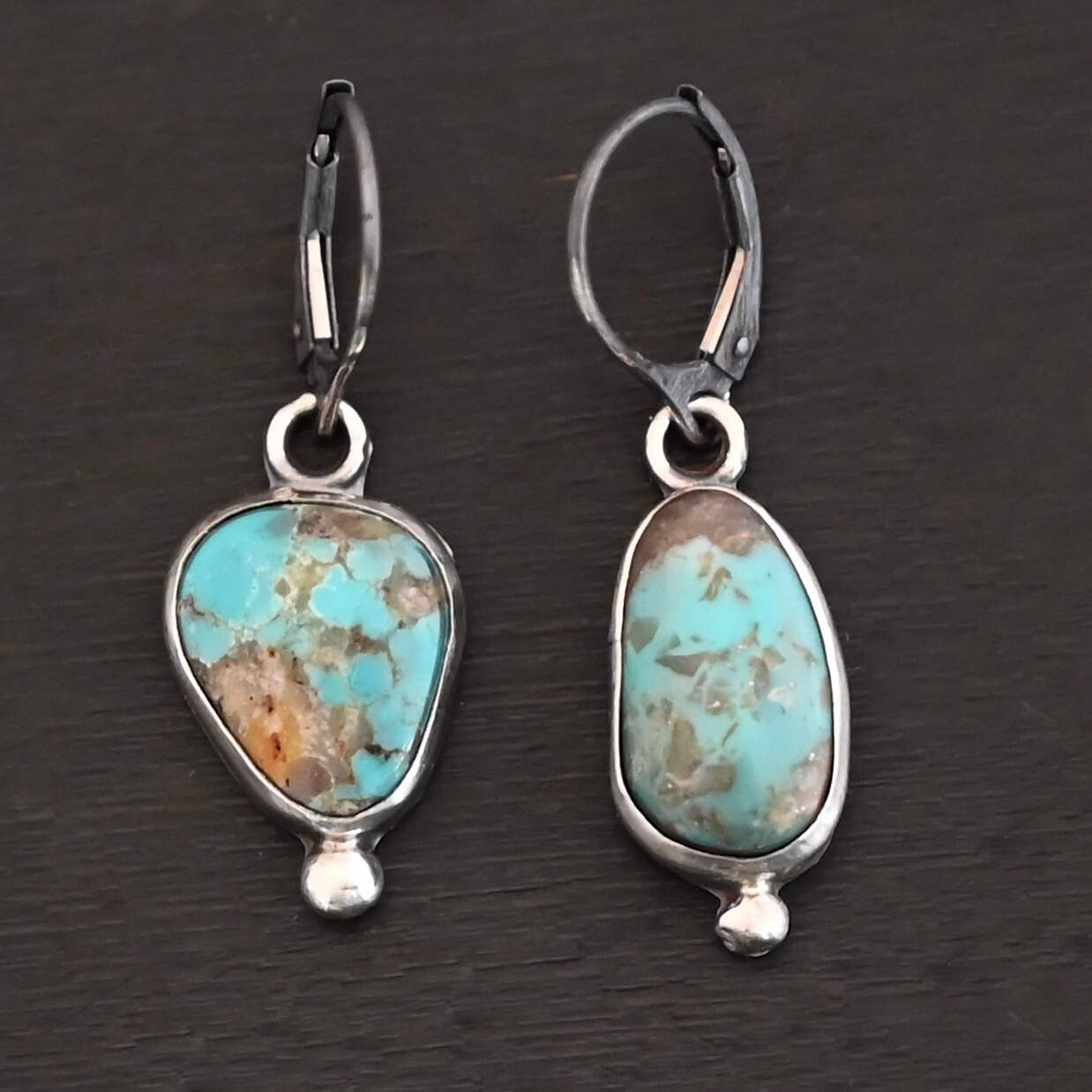 Elma Earrings "Elma" Earrings. Sterling Silver & Turquoise. Left earring has a triangular shape and right earring is an oval turquoise. Each one has a ball of silver beneath it and silver ear wires.