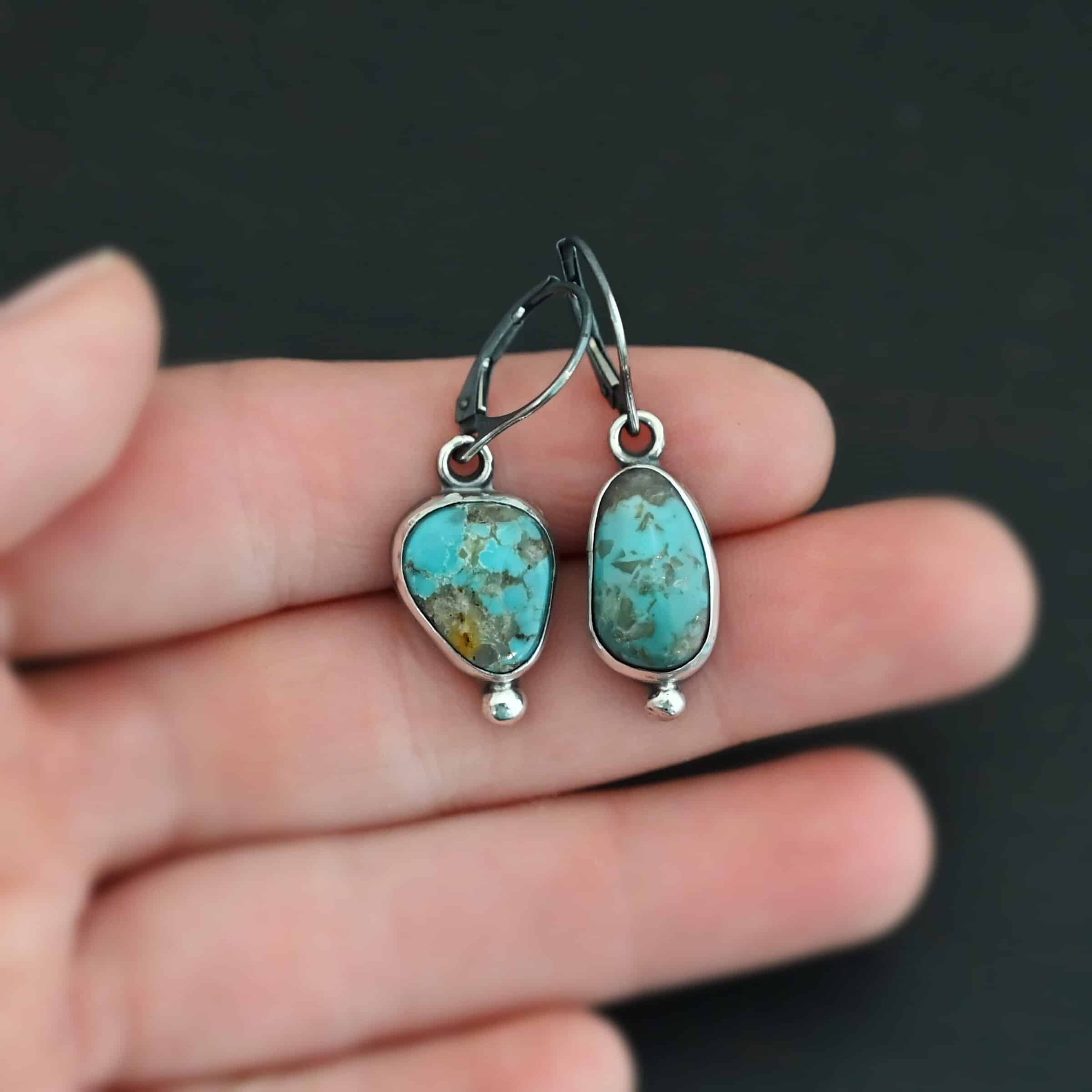 Elma Earrings "Elma" Earrings. Sterling Silver & Turquoise. Left earring has a triangular shape and right earring is an oval turquoise. Each one has a ball of silver beneath it and silver ear wires.